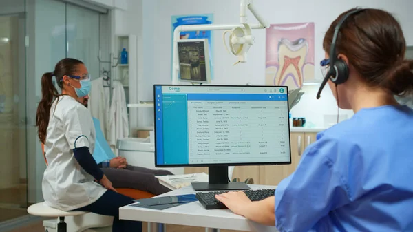 Sjuksköterska talar med patienter som använder headset boka tandläkarbesök — Stockfoto