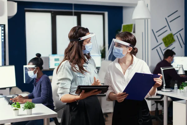 Предпринимательницы в защитных масках от коронавируса, стоящие на рабочем месте — стоковое фото