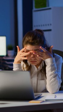İş yerinde baş ağrısı çeken stresli iş kadını fazla mesai yapıyor.