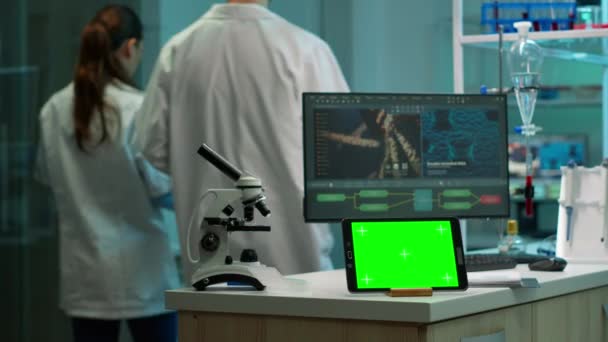 Chimici testare l'evoluzione del virus con tablet schermo verde nella parte anteriore sulla scrivania — Video Stock