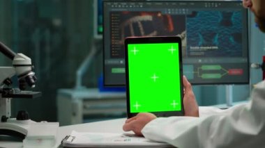 Erkek kimyager elinde yeşil ekran tableti tutuyor.