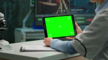 Kimyager kadının elinde tabletle yeşil bir maket tutarken görüntüsü.