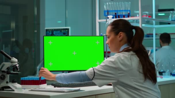 Ученый, анализирующий образец крови и печатающий на компьютере с помощью хроматического ключа — стоковое видео