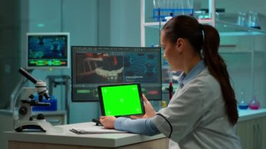 Biyokimyacı yeşil ekran tableti kullanarak laboratuvarda oturuyor.