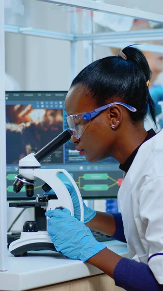 Czarna biochemiczka siedząca w laboratorium i analizująca badania krwi — Zdjęcie stockowe