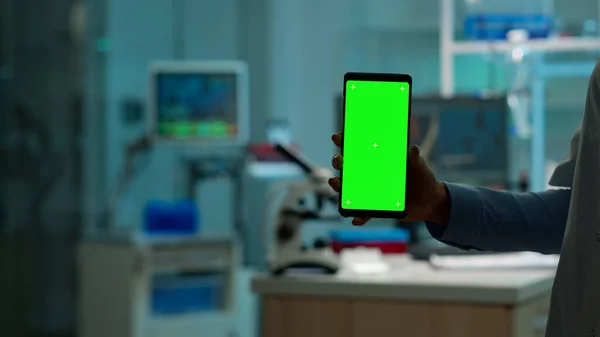 Close up of chemists hand holding phone with green screen — Stock fotografie