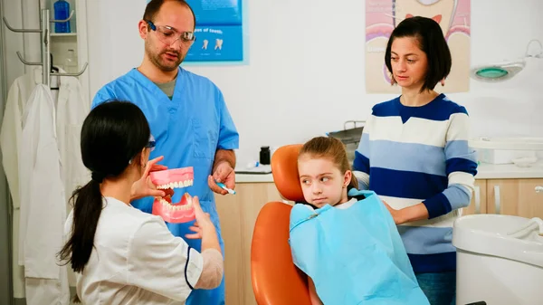 Врач показывает ребенку правильную гигиену зубов, используя макет скелета зуба — стоковое фото