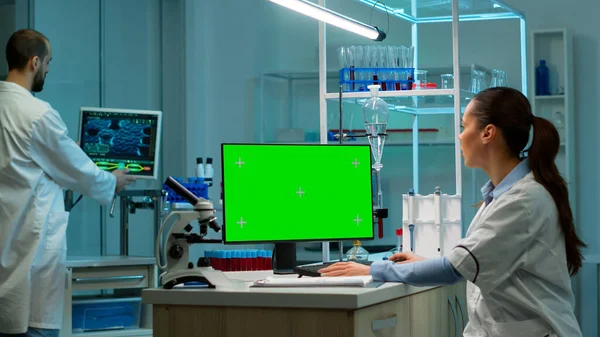 Biochimico seduto sul posto di lavoro utilizzando il pc schermo mock-up verde — Foto Stock