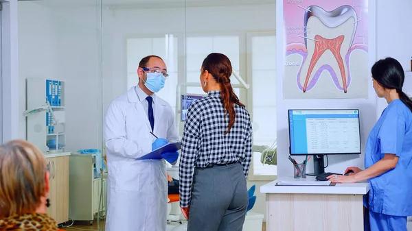 Dentist doctor interrogating woman taking notes on clipboard — Stock Photo, Image