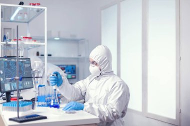 İnsan bilimadamı mikro pipeti cam şişeden çözeltiyle dolduruyor.