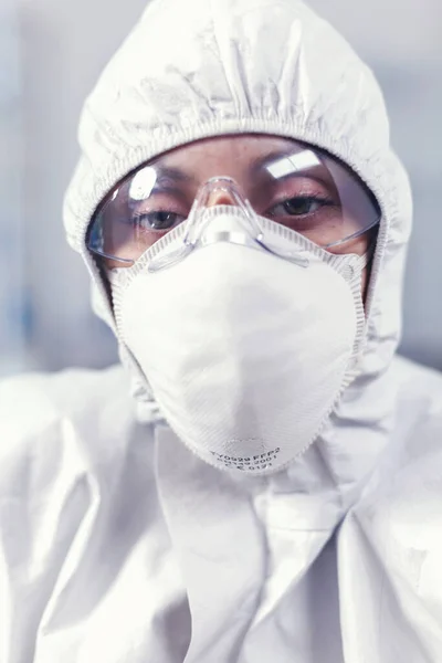 Микробиолог, сидящий в лаборатории и смотрящий в камеру — стоковое фото