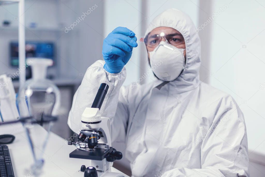Scientist looking at a microscope slide dressed in coverall
