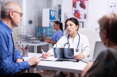 Doktor yaşlı adamla röntgen hakkında konuşuyor.