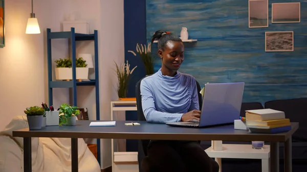 Africano sorrindo freelancer digitando no computador e escrevendo para fazer lista — Fotografia de Stock