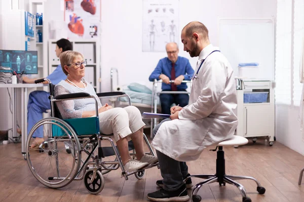 Oudere vrouw in rolstoel op doktersafspraak — Stockfoto
