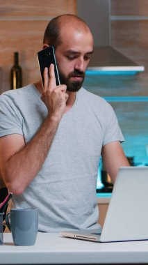 Bilgisayarda yazan ve telefonda konuşan uzaktan çalışan.