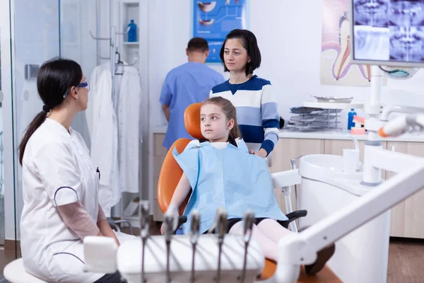 Родитель с маленькой девочкой слушает детского стоматолога говорит о гигине рта — стоковое фото