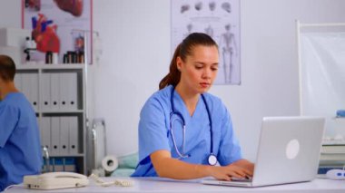 Hastane resepsiyonunda telefona bakan kadın hemşire.