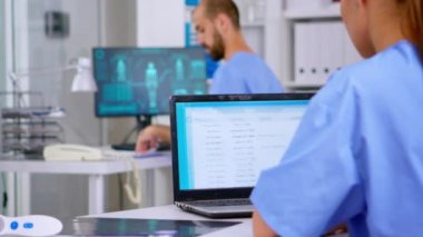 Profesyonel doktor asistanı laptoptaki tıbbi kayıtları kontrol ediyor.
