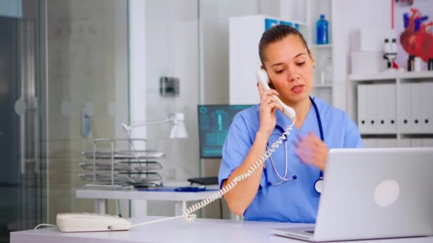 Medische assistent aan de telefoon met patiënt die röntgenfoto 's analyseert — Stockvideo