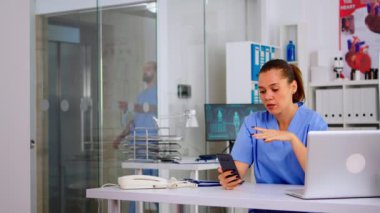 Hemşire elinde akıllı telefon, hastayla teletıp yapıyor.