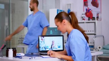 Tıp öğrencisi kıdemli doktorla video sağlık konferansı sırasında konuşuyor.