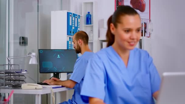 Mężczyzna pielęgniarka odbiera telefon w recepcji szpitala — Wideo stockowe