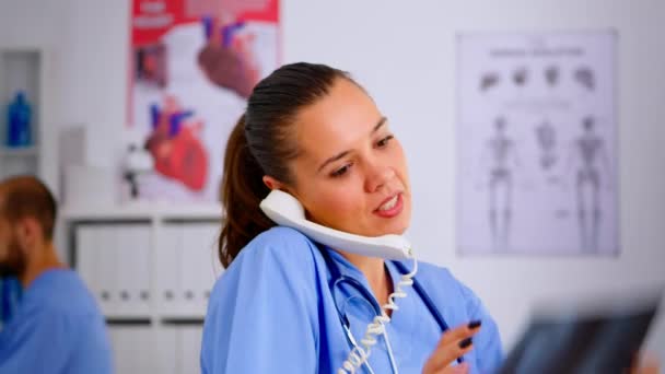 Close-up de assistente atendendo telefone verificando paciente radiografia — Vídeo de Stock