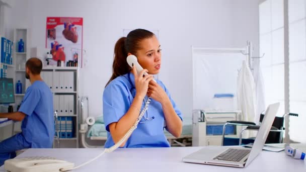 Hastane telefonuna bakan hemşire hastanın röntgen sonuçlarını kontrol ediyor. — Stok video