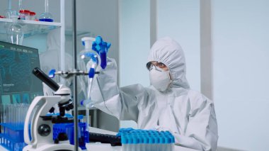 Laboratuvardaki bilim adamı mavi sıvıyla testler yapıyor.