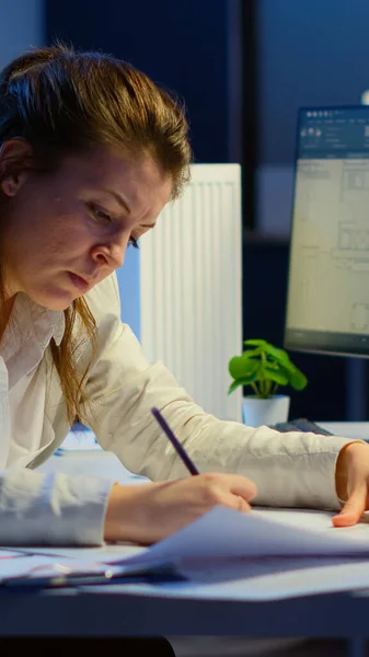 Arquitecta mujer con exceso de trabajo analizando y haciendo coincidir planos — Foto de Stock