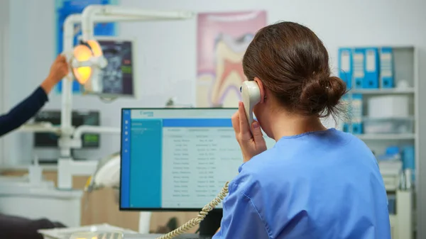 Ortodontist sjuksköterska talar i telefon boka tandläkarbesök — Stockfoto