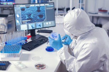 Tıp laboratuarındaki doktor petri kabında virüs üretiyor.