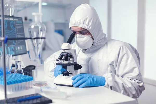 Microbiologist with protection glasses using microscope — Stock Photo, Image