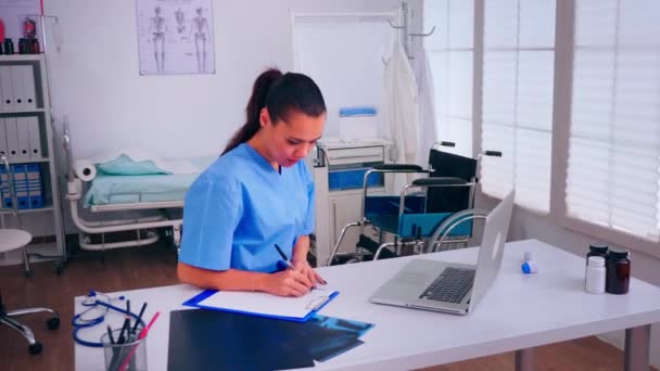 Gesundheitsassistentin macht sich Notizen auf Klemmbrett bei der Arbeit im Krankenhaus — Stockvideo