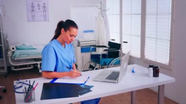 Üniformalı terapist doktor asistanı panoya yazı yazıyor.