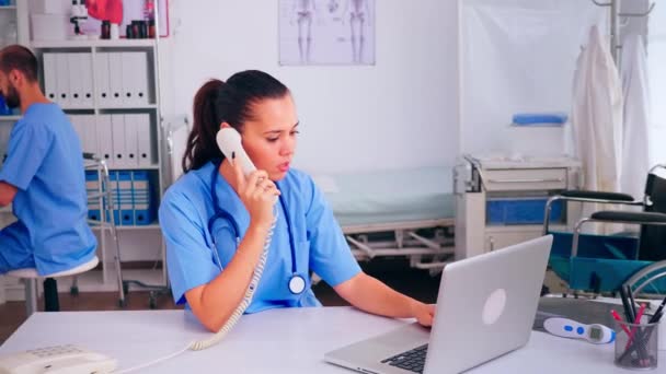 Asystent chirurga dyskutujący z pacjentem przez telefon — Wideo stockowe