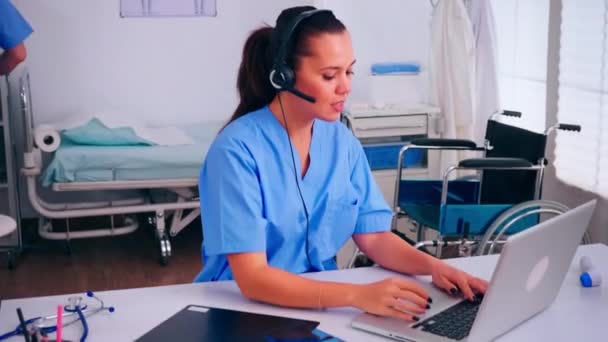 Penerima tamu, operator berbicara online dengan pasien menggunakan headphone — Stok Video