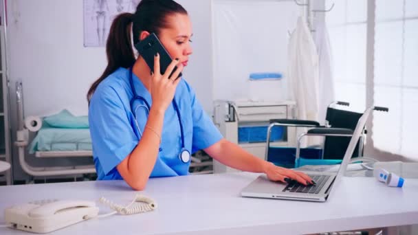 Krankenschwester spricht am Handy mit Arzt über Patientenliste — Stockvideo