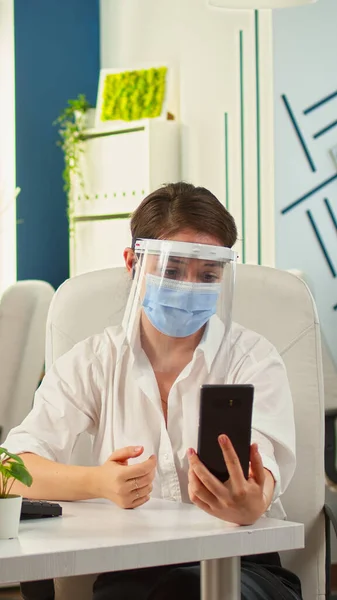 Emploee with face mask using having videocall on smartphone — Stock Photo, Image