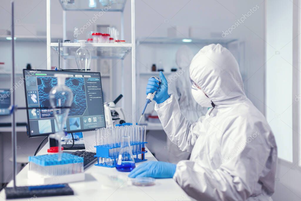 Laborant working with automatic pipette and test tubes