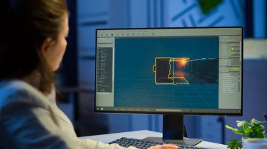 Kadın oyun tasarımcısı bilgisayar ekranına bakıyor gece geç saatlere kadar çalışıyor