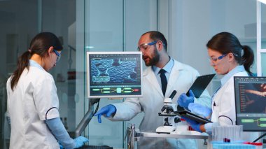 Mikrobiyoloji ekibinden bilim adamları virüs gelişimini tartışıyor.