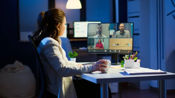 Employee discussing with partners online using webcam at night
