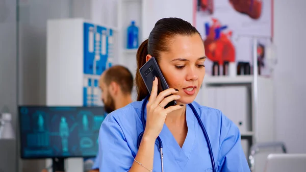 Assistente medico che parla allo smartphone con un medico che chiede consiglio — Foto Stock