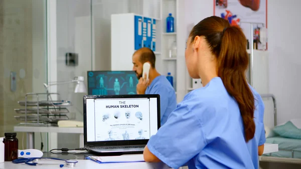 Doctor assistant analyzing digital human skeleton on laptop