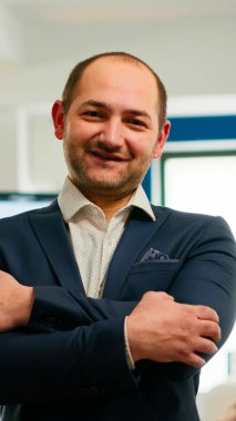 Genç adam proje yöneticisi kameranın önünde gülümsüyor.