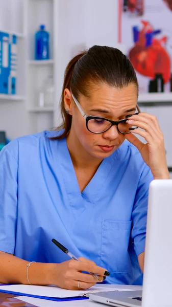 Exhausted therapist working on laptop and taking off the glasses — Stock Photo, Image