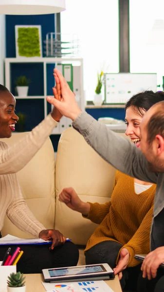 Diverse team of successful young entrepreneurs sharing high-five celebrating success