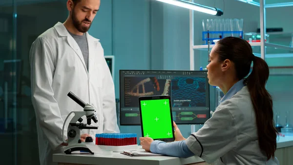 Вчений-хімік використовує зелений макет планшета, що сидить за столом — стокове фото